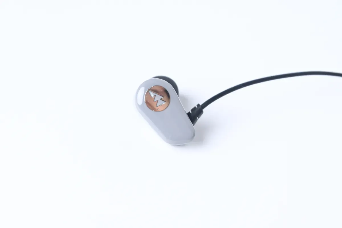 Accel earpiece — copper logo badge detail